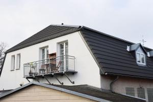 uma casa branca com um telhado preto e uma varanda em gemütliche & ruhige Unterkunft em Erftstadt
