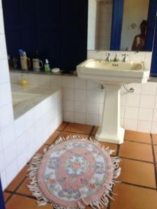 un bagno con lavandino e tappeto sul pavimento di Linda Fazenda Centenária a Santa Rita do Sapucaí