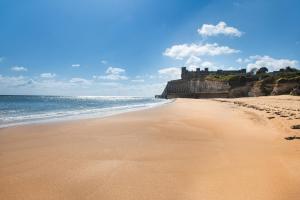 a beach with the ocean and a castle in the background at Art Deco Coastal Apartment with Private Garden in Broadstairs