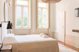 1 Schlafzimmer mit einem großen weißen Bett und 2 Fenstern in der Unterkunft Alameda Suites - River Guest House in Porto