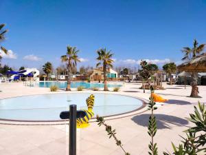 un complejo con piscina y palmeras en camping les sables du midi, en Sérignan
