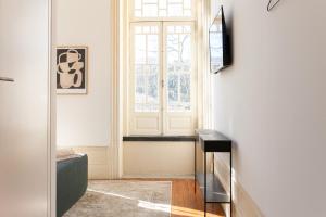 einen Flur mit einer Tür, einem TV und einem Fenster in der Unterkunft Alameda Suites - River Guest House in Porto