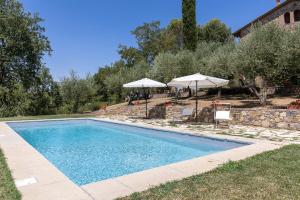 una piscina con due ombrelloni accanto a una casa di Poggio Vitignano Charming Cottage With Pool and Parking a Pianella