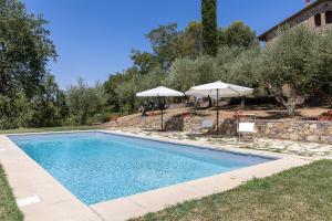 a swimming pool with two umbrellas next to a house at Poggio Vitignano Charming Cottage With Pool and Parking in Pianella