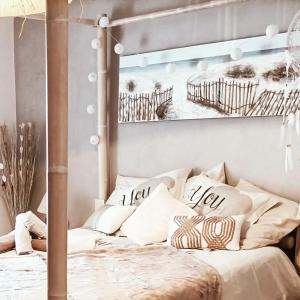 a bed with white pillows and a picture of a pier at Gîte 3 étoiles avec SPA, 2 Chambres LE LOGIS DE PEARL in Salles-sur-Mer