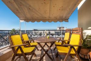 eine Terrasse mit gelben Stühlen und einem Tisch auf dem Balkon in der Unterkunft Egnatia flat 2 in Thessaloniki