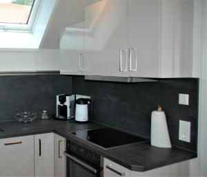 a kitchen with white cabinets and a black counter top at GASTHAUS Porzelt -Ferien im Weingut - Wohnung 2 in Klingenmünster