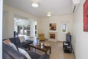 ein Wohnzimmer mit einem Sofa, einem Tisch und einem TV in der Unterkunft Protaras Delfini Villa Dv4 in Protaras