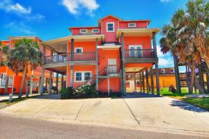 a large orange building with palm trees in front of it at 6BDRM Beach Home - Oceanviews - Recently Renovated - Shared Pool & HotTub in Port Aransas