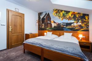 a bedroom with a bed with a painting on the wall at Hotel Jelínkova vila in Velké Meziříčí