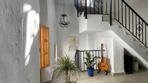a hallway with a staircase with a guitar and plants at Casa Palma in Cómpeta