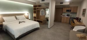Cet appartement comprend une chambre avec un grand lit blanc et une cuisine. dans l'établissement Armonia Apartments, à Keramoti