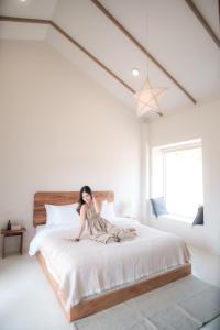 una mujer sentada en una cama en un dormitorio en Monko Villa, en Pai