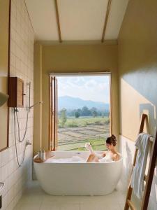 a woman in a bath tub in a bathroom with a window at Monko Villa in Pai
