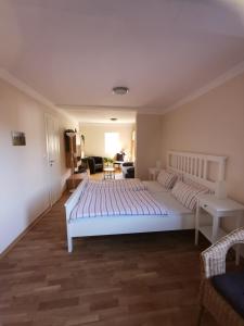 a bedroom with a large white bed and a living room at Pension am Rheinsteig in Leutesdorf