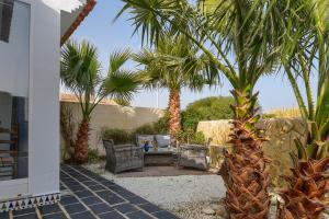 une terrasse avec des palmiers, une table et des chaises dans l'établissement El Boticari, à Dénia