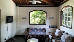 a living room with a couch and a window at Casa com 6 Suites, piscina e estacionamento in Ilhabela