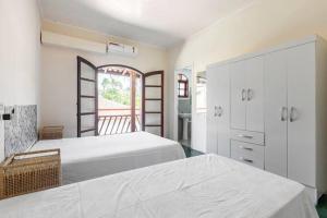 ein weißes Schlafzimmer mit zwei Betten und einem Fenster in der Unterkunft Casa com 6 Suites, piscina e estacionamento in Ilhabela + 43 Fotos