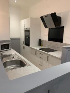 a white kitchen with a sink and a microwave at DS Study or Visit in Dundee