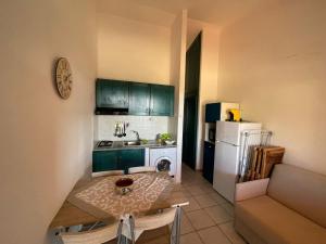 Una cocina con gabinetes verdes, una mesa y un refrigerador. en Appartamento- La Falata, en Costa Paradiso