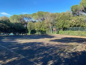 een lege tennisbaan met bomen op de achtergrond bij Appartamenti sul mare Villa il Fortullino in Case Fortullino