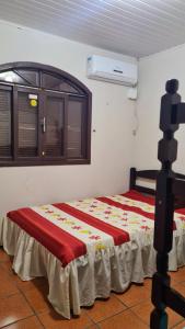 a bedroom with a bed with a red and yellow blanket at Casa praia Enseada in São Francisco do Sul