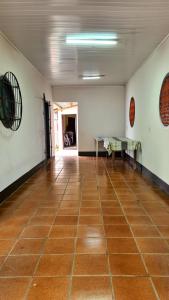 an empty room with a tile floor and a room with tables at Casa praia Enseada in São Francisco do Sul