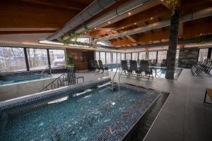 a large swimming pool in a building with chairs and tables at Hotel Yara in Vişeu de Sus