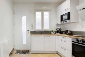 eine weiße Küche mit einer Spüle und einer Mikrowelle in der Unterkunft Le Cordouan in La Rochelle