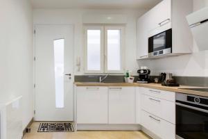 a white kitchen with a sink and a microwave at Le Cordouan in La Rochelle