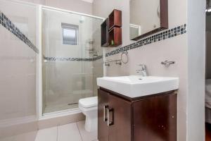 a bathroom with a sink and a shower and a toilet at Paradise Guest House in Roodepoort