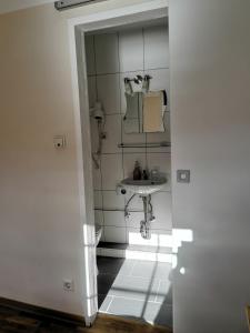 Baño blanco con lavabo y espejo en Pension am Rheinsteig, en Leutesdorf