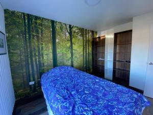 a bedroom with a blue bed with a forest view at Linda y cómoda casa individual in Llanquihue