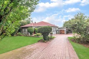 a house with a brick driveway in front of a yard at Paradise Guest House in Roodepoort