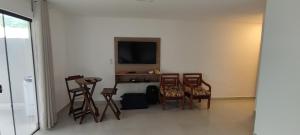a room with chairs and a table and a television at Casa do Sérgio, Lindo loft-02 moderno e confortável. in Paraty