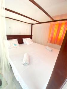 ein weißes Bett mit einem rollenden Handtuch drauf in der Unterkunft Sanderling Silent Beach Cabanas in Tangalle