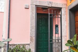 zielone drzwi przed różowym domem w obiekcie Casa Caterina Appartamento al Centro di Taormina w Taominie