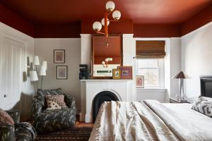 a bedroom with a bed and a chair and a fireplace at Blind Tiger Portland - Carleton Street Guest House in Portland