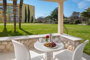 a table and chairs with a bowl of fruit on a patio at Residence Garden Istra Plava Laguna in Umag