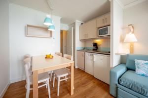 a kitchen and dining room with a table and a blue couch at Résidence Pierre & Vacances Cannes Verrerie in Cannes