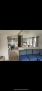 a living room with a blue couch and a kitchen at Seaside chill in Prestatyn