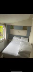 ein weißes Bett in einem Zimmer mit Fenster in der Unterkunft Seaside chill in Prestatyn