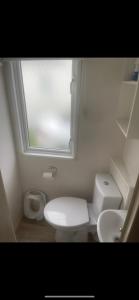a white bathroom with a toilet and a window at Seaside chill in Prestatyn