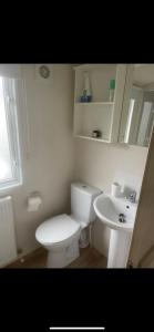 a white bathroom with a toilet and a sink at Seaside chill in Prestatyn