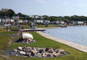 米勒姆的住宿－Plot 8 Lakeside Cabin, Wyldecrest, Millom，坐在水体旁的草上的小船