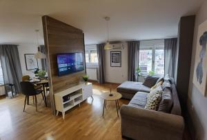 ein Wohnzimmer mit einem Sofa, einem TV und einem Tisch in der Unterkunft Sun Deluxe Apartment in Banja Luka