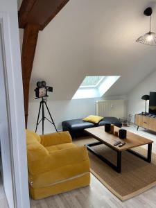uma sala de estar com um sofá amarelo e uma mesa em Le Chic Vintage em Contrexéville