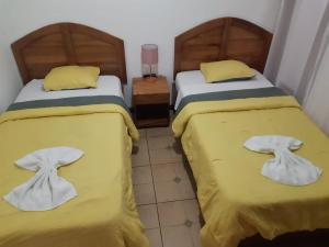2 camas en una habitación con sábanas amarillas y toallas en Boutique Hotel Calle 20, en San José
