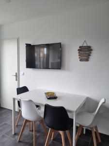 een witte eettafel met stoelen en een tv aan de muur bij Chez peggy in Metz