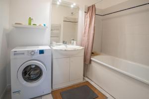 baño blanco con lavadora y lavamanos en LaConciergerieJonzac, Appartement Le Carré des Antilles 2, en Jonzac